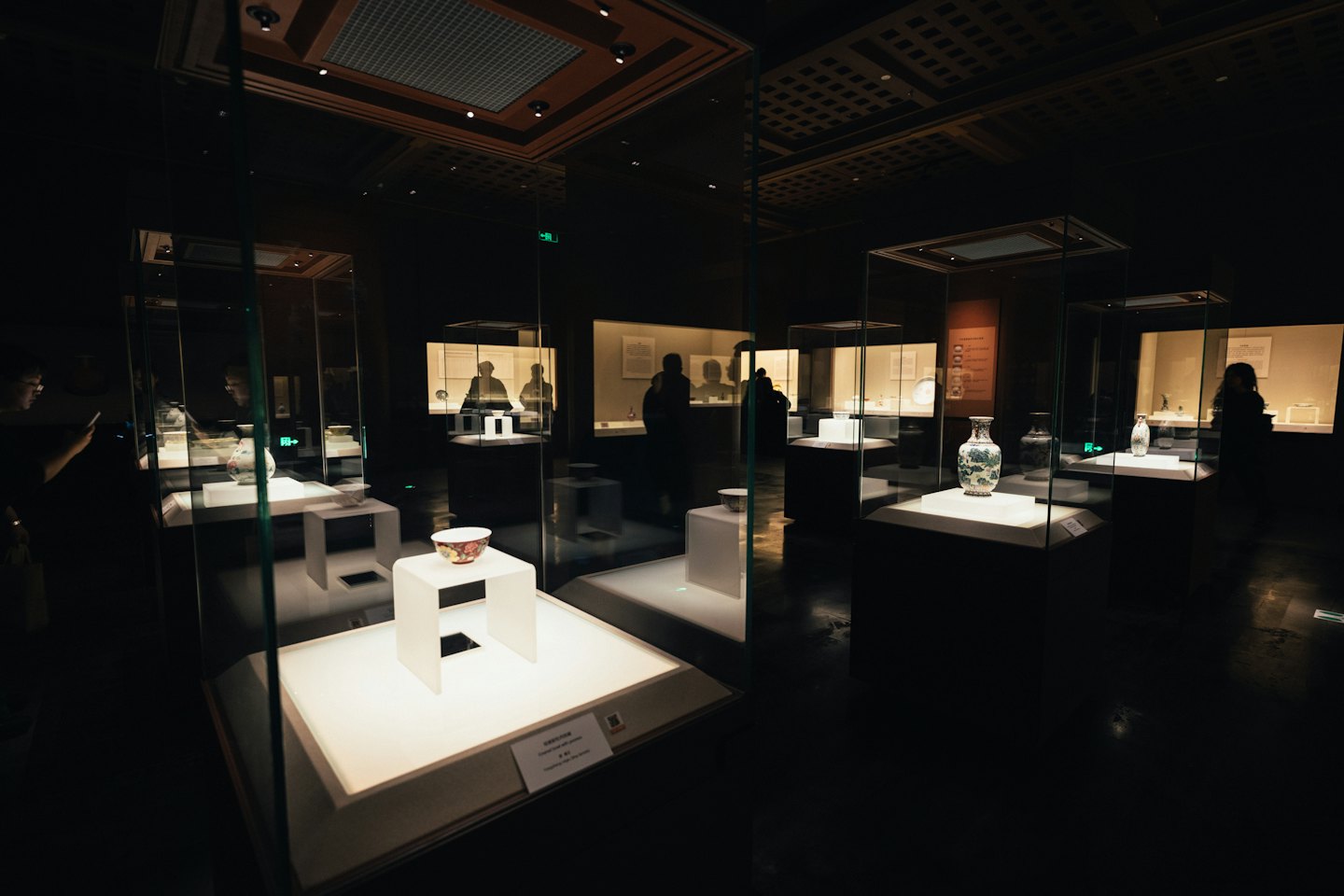Visitatori osservano manufatti in ceramica in teche di vetro di un museo.